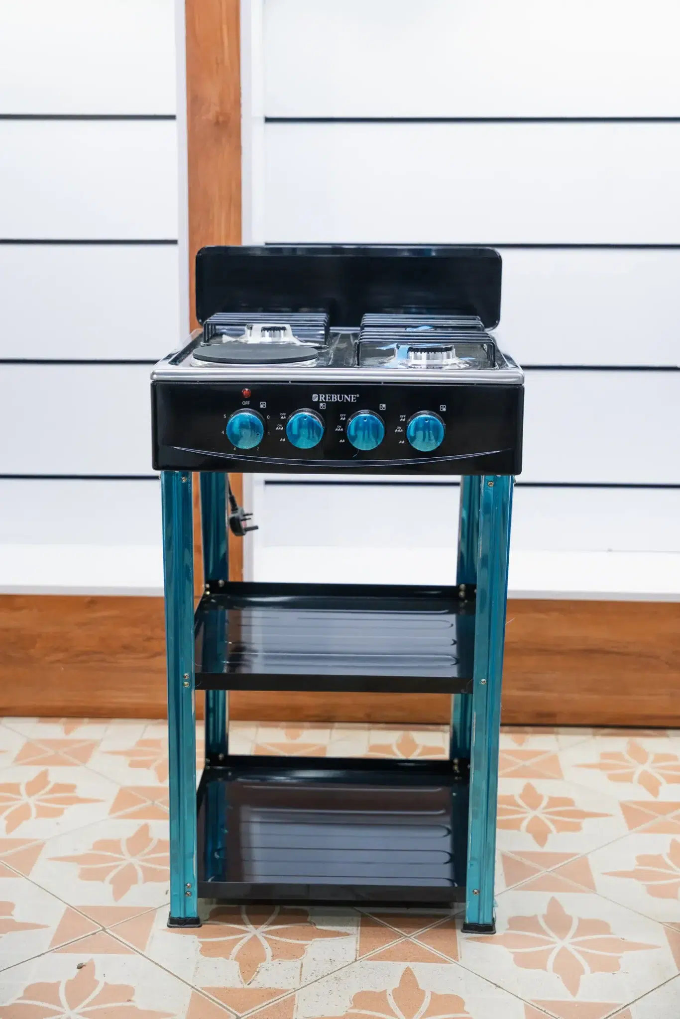 Rebune 50x50 Standing Cooker (3 Gas + 1 Electric) with Shelves 3 Rebune 50x50 standing cooker with blue control knobs and two storage shelves at Tael Appliances.