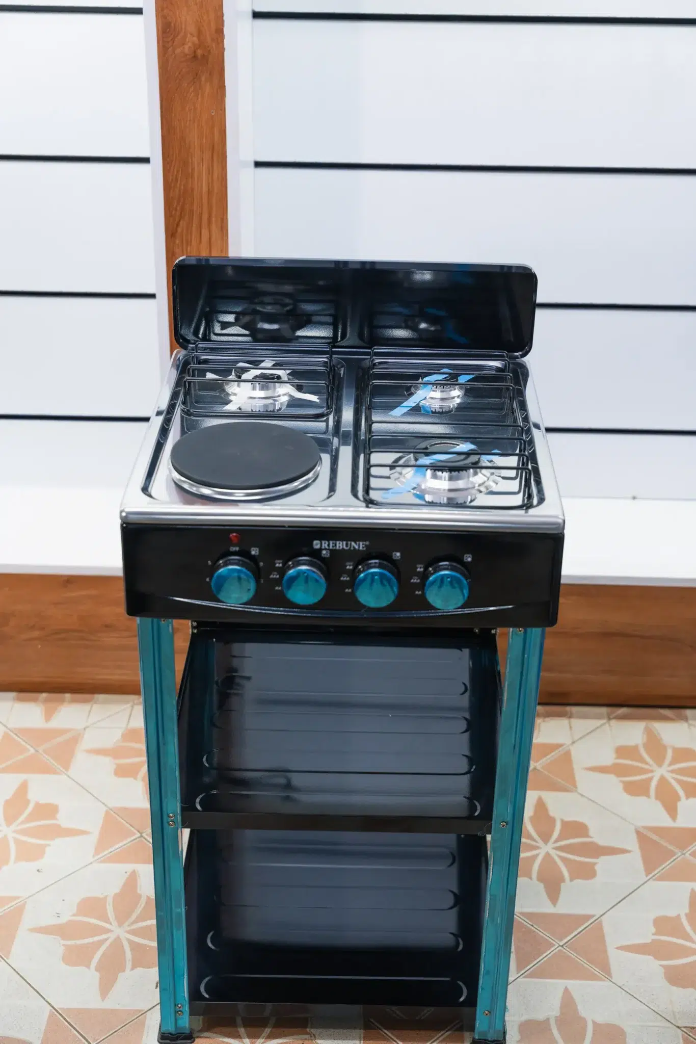 Rebune 50x50 Standing Cooker (3 Gas + 1 Electric) with Shelves 2 Rebune 50x50 standing cooker front view showing the stainless top and black storage shelves at Tael Appliances.