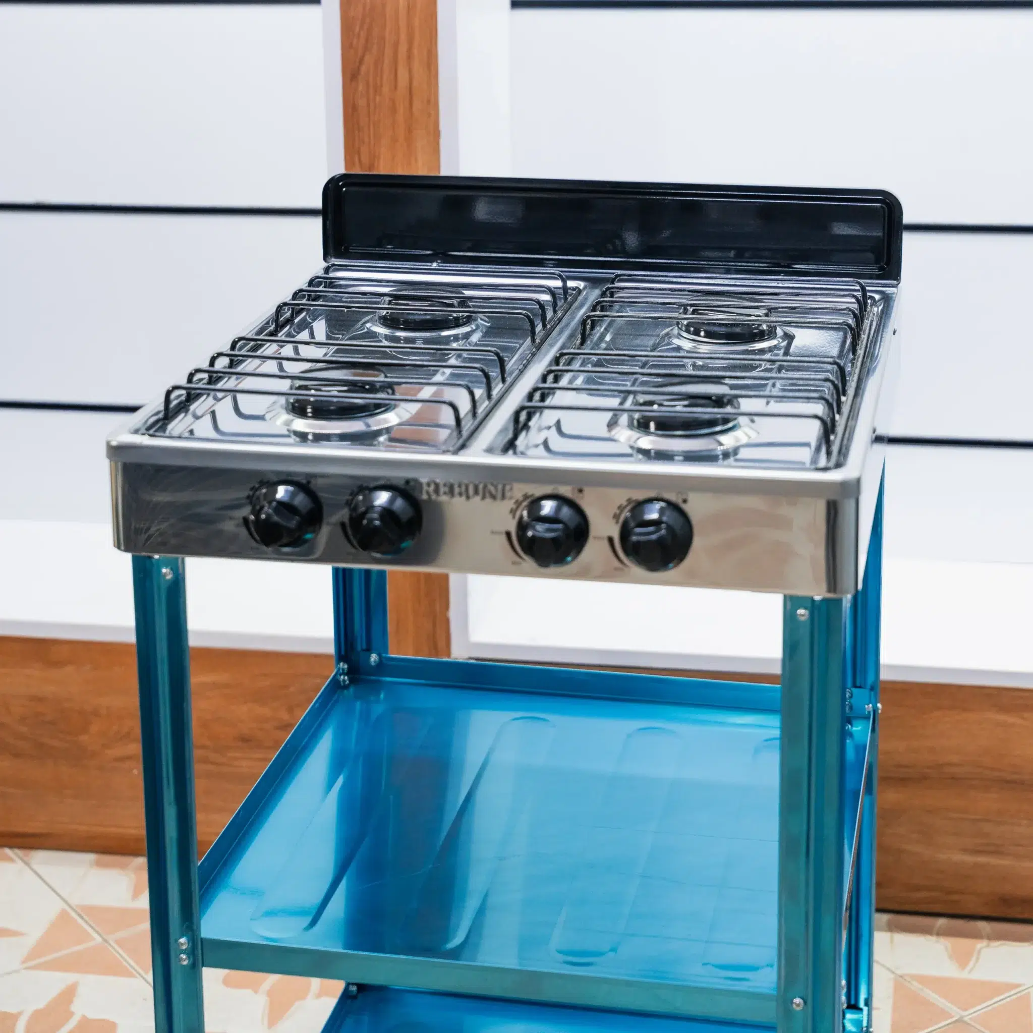 Rebune 4 Burner Gas Cooker 50x50 with Storage Shelves 4 Rebune 4 burner standing gas cooker, angled view of the stainless steel top and splash guard at Tael Appliances.